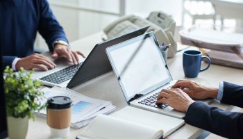 Cropped image of business people working on laptops in office